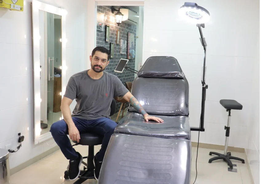 Lucas Franca ao lado da bancada de tatuagem em seu estúdio